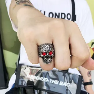 Macro shot of retro silver skull ring with red gemstone eyes on male model hand