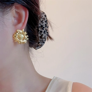 Detailed close-up of 18K gold plated sunflower stud earring on model with vintage finish