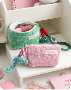Detailed view of fuzzy plush coin purses in mint green and pink with braided rope handles