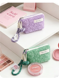 Detail of plush fuzzy coin purses in purple and green with contrast braided wrist straps