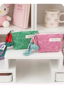 Macro detail of plush coin pouches in green and pink with colorful braided strap