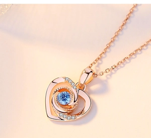 Macro d'un pendentif cœur en or rose avec une pierre bleue et de petits diamants étincelants