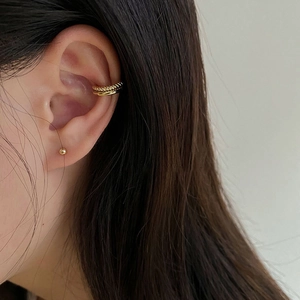 Detail of gold layered ear cuff and stud earring set shown on a model ear