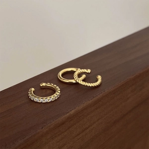 Detailed view of three gold-plated ear cuffs featuring rhinestones and twisted rope designs