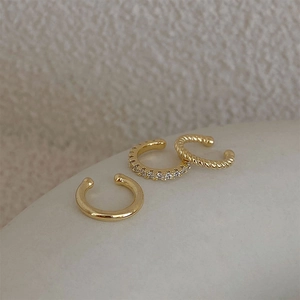 Macro view of three-piece vintage gold ear cuffs featuring paved zircons and twist texture