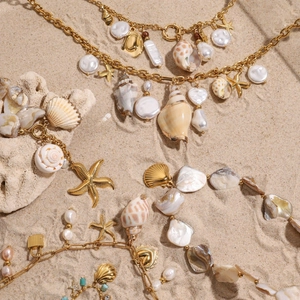 Golden titanium steel shell necklace with pearls and starfish on a beach scene