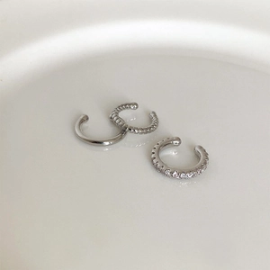 Close-up of three silver ear cuffs including smooth, twisted, and cubic zirconia bands