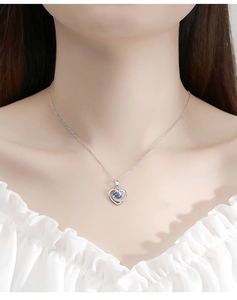 Détail du collier coeur en argent avec pierre bleue sur le cou du mannequin