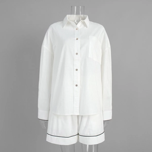 Détail de l'ensemble chemise blanche avec boutons en bois et liseré noir sur tissu aéré