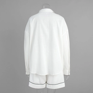 Détail de l'ensemble chemise en lin blanc montrant la texture et l'ourlet contrasté