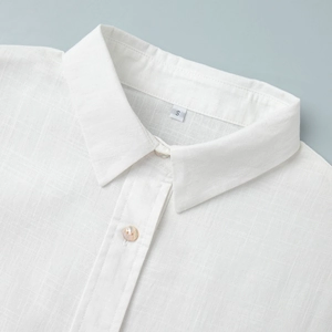 Gros plan du col de chemise en lin blanc avec boutons nacrés et texture naturelle