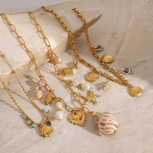Detail of gold ocean-themed jewelry with seashells, pearls and starfish on stone