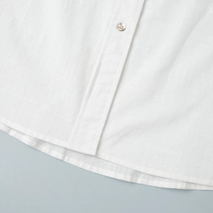 Détail d'une chemise blanche en lin montrant la texture du tissu et le bouton