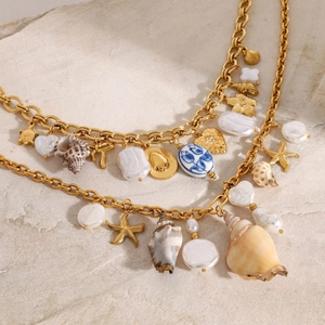 Detail of gold chain necklace featuring sea shell, starfish, and baroque pearl charms