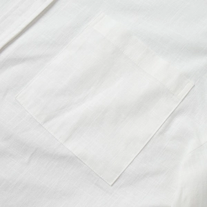 Vue détaillée de la poche avant et des coutures sur une chemise blanche en lin
