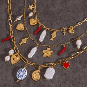 Macro detail of layered gold-plated necklace with baroque pearls and ocean-themed charms