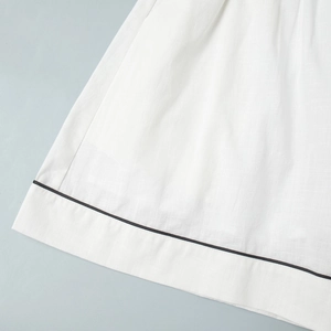 Gros plan détaillé de l'ourlet de chemise en lin blanc avec passepoil noir contrastant