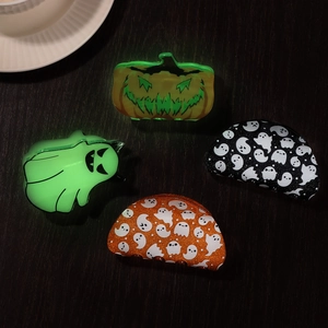 Halloween claw clips set with pumpkin and luminous ghost designs on dark wood background