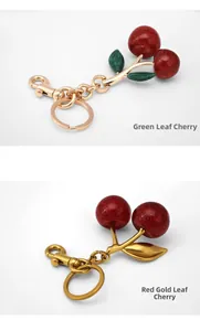 Close-up of glitter cherry keychains with green and gold leaf details and metal clasps