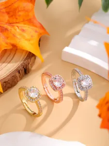 Close-up of three square halo diamond rings in gold and silver on an autumn wood setting