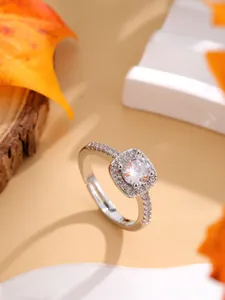 Close-up of a silver halo ring with a large round cubic zirconia on wood background