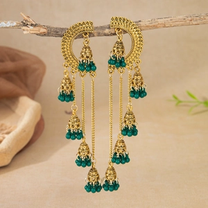 Detail of vintage gold Jhumka earrings with green beads hanging on a wooden branch