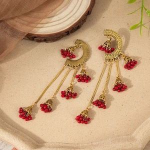 Detail of vintage gold alloy earrings with red bead tassels and jhumka bell design
