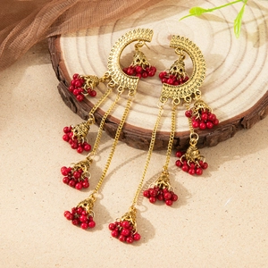 Detail of vintage gold Indian style earrings with red beads and dangling bell tassels