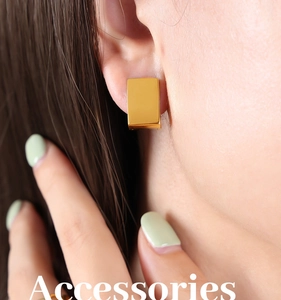 Close-up of minimalist golden rectangular hoop earrings worn by a model for a modern look