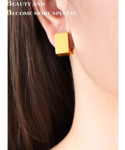Close-up of stylish gold square hoop earrings worn by a model with polished mirror finish