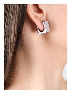 Macro shot of silver square geometric hoop earring with polished finish on model