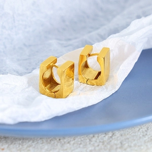 Minimalist gold square hoop earrings displayed on a stylish blue ceramic tray background