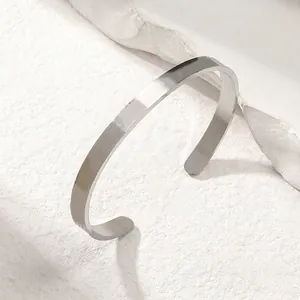 Polished stainless steel minimalist cuff bangle on a natural stone textured background