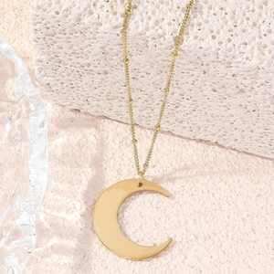Polished gold crescent moon pendant necklace with delicate bead chain on textured stone