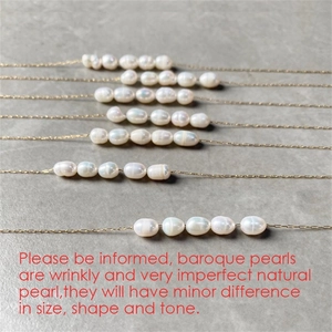 Detail of baroque pearl necklaces with thin gold-plated chains on dark stone surface