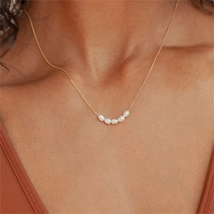 Close-up of five freshwater pearls arranged on a delicate gold-plated stainless steel chain