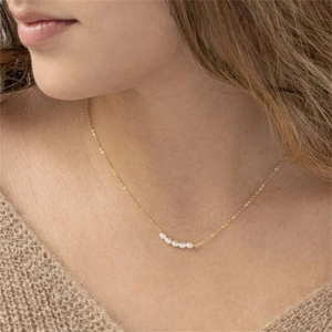 Close-up of elegant gold chain necklace featuring five natural freshwater pearls on a model