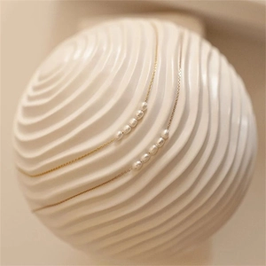 Detailed shot of two gold-plated necklaces with five white freshwater pearls on art prop
