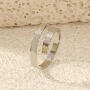 Close-up of minimalist silver double-layer spiral open ring on textured beige surface