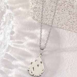 Polished silver stainless steel necklace with flame cutout pendant on stone display