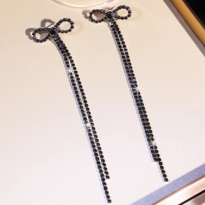 Macro detail of elegant black rhinestone bow drop earrings with long tassel chain fringe