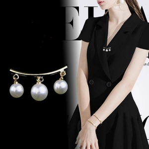 Detail of elegant gold brooch with three white pearls on black suit lapel