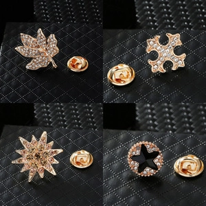 Detail shot of four gold men's suit brooches with rhinestones and butterfly clasps