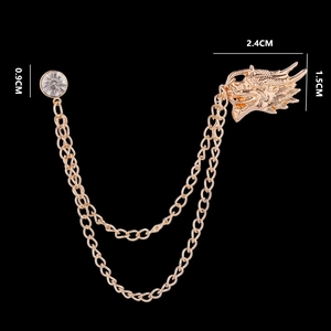 Detailed view of golden dragon brooch with crystal stud and dual chain tassels