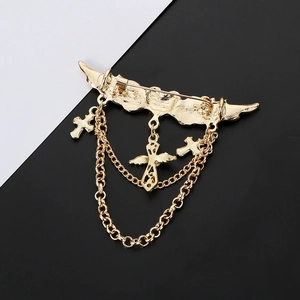 Detailed view of golden wing brooch with hanging metal chains and triple cross pendants