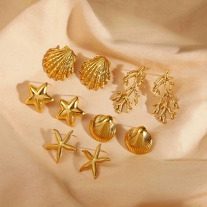 Detailed set of five 18k gold starfish and coral stud earrings on champagne silk fabric