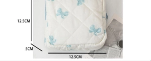 Dettaglio della borsa per trucco in cotone trapuntato con fiocchi blu e misure 12,5x12,5cm