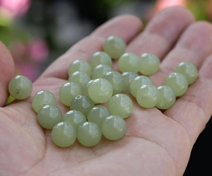 Macro shot of light green natural jade beads held in hand for DIY jewelry making