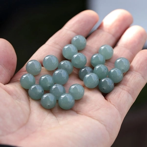 Macro shot of polished light green natural jade beads held in hand for DIY jewelry