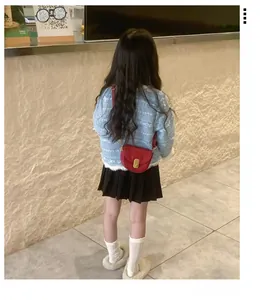 Toddler girl wearing light blue tweed jacket with a bright red mini saddle crossbody bag